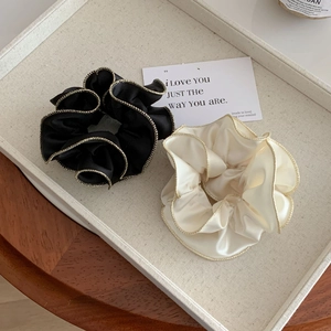 Chouchous élégants en satin noir et crème avec bordure dorée sur un plateau