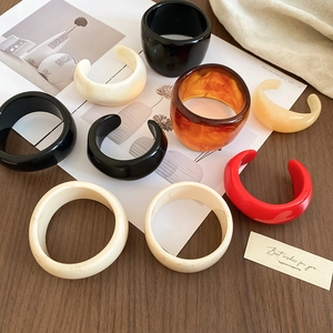Detailed view of acrylic resin bangle set in amber and cream on a vintage wooden table
