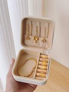 Handheld view of mini travel jewelry box showing ring slots and necklace hooks