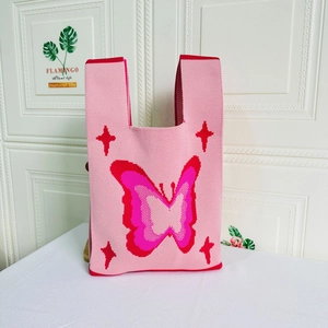 Detailed close-up of a pink knitted tote bag featuring a red butterfly and star pattern