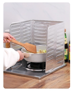 Foldable aluminum oil splash guard shielding gas stove and wall in a kitchen setting