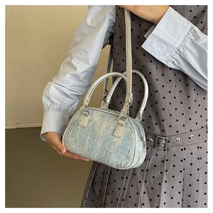 Detailansicht glitzernder Silberpailletten auf einer hellblauen Zylinder-Handtasche mit Riemen