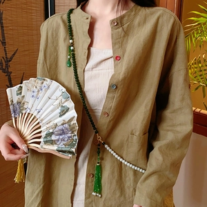 Détail du collier de perles vertes avec perles blanches et pompon sur chemise kaki