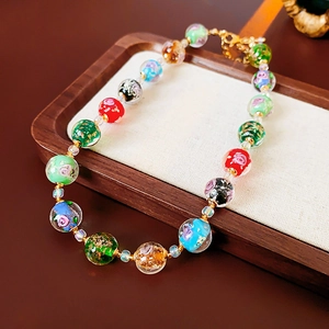 Detail of colorful glass beads necklace featuring floral patterns and gold foil elements