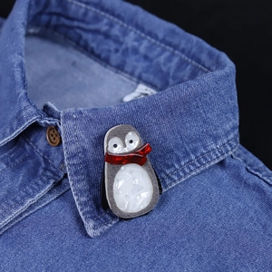 Handmade acrylic penguin brooch with red scarf pinned on a blue denim shirt collar