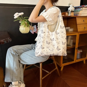 Detailed shot of white tote bag featuring lace butterfly patterns and fringe texture