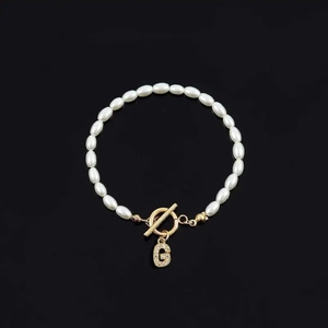 Fashion pearl bracelet featuring white oval pearls and a sparkling gold letter G pendant