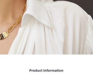 Detail of gold chain necklace with oval links paired with a white textured shirt