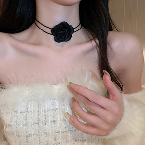 Close-up of a handmade black fabric rose necklace worn on a woman's neck for an elegant look