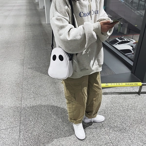 Detail of a white ghost-shaped PU leather crossbody bag featuring black oval eyes
