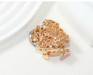 Close-up of the golden openwork metal brooch featuring a pattern of small heart cutouts