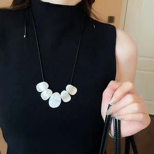 Detail of irregular white shell pendants on a black leather cord necklace for women
