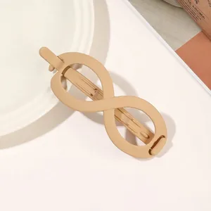 Detail of a matte beige infinity hair claw clip resting on a white ceramic plate