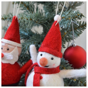 Detailed view of handmade wool felt snowman and Santa Claus ornaments on a Christmas tree