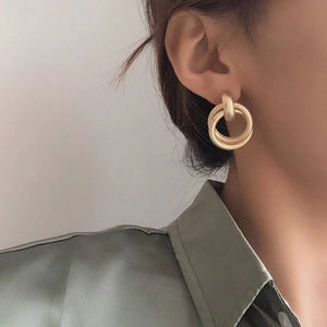 Minimalist matte gold double hoop earrings worn on ear with elegant satin blouse