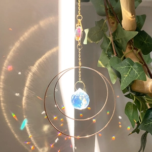 Detail eines hängenden Kristall-Sonnenfängers mit goldenen Ringen und facettierten Prismen