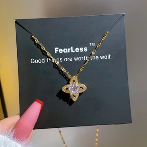 Golden titanium steel necklace with starburst zircon pendant on a black gift card