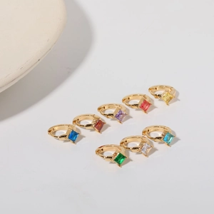 Macro shot of colorful square-cut zircon earrings in gold settings on white background