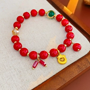 Détails d'un bracelet en perles rouges avec pendentif phénix doré et charmes de chance