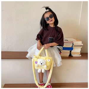 Kids yellow plush crossbody bag with 3D teddy bear and floral charms on a child model