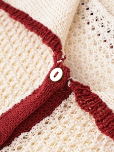 Close-up of knit fabric texture with white button detail in cream and dark red colors