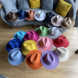 Top view of fedora straw hats in 19 vibrant colors arranged on a white table and sofa