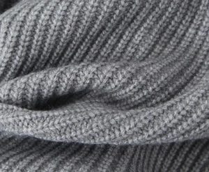 Gros plan sur un tissu en maille grise montrant la texture douce et les détails côtelés