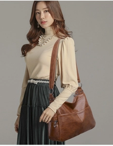 Detail of brown lychee texture PU leather bag with side zipper and wide shoulder strap