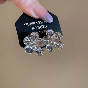 Polished 925 sterling silver flower stud earrings held in hand for a stylish minimalist look