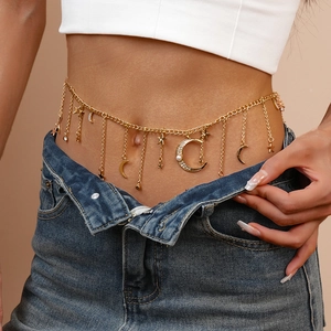 Detail of gold waist chain featuring star moon charms and pearls on model waist