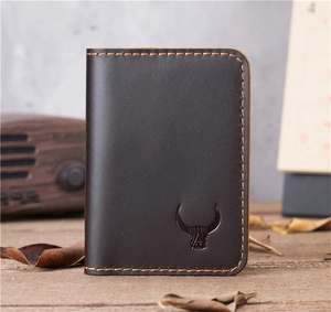 Detail of dark brown vintage leather card holder with embossed bull head on wooden desk