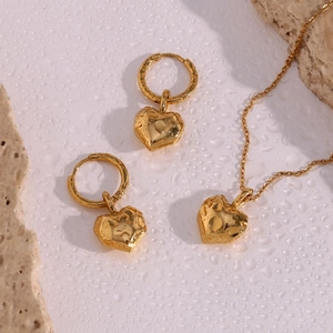 Detail of golden heart jewelry set with hammered texture on necklace and earrings