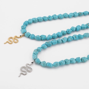 Macro detail of turquoise beaded necklaces with gold and silver snake pendants