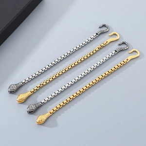 Close-up of punk snake head clasp on box chain bracelets in gold and silver finish