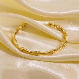 Detailed view of gold plated titanium steel open cuff bangle with bamboo texture on silk