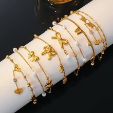Macro shot of gold bracelets with heart and bow charms on a white cylinder stand