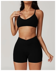 Detail view of black V-neck sports bra with thin straps and V-shaped cross waist shorts