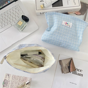 Detail of light blue checkered makeup bag interior showing storage space for toiletries
