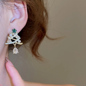 Close-up of sparkling Christmas tree earrings with green crystals and pearl drops on model