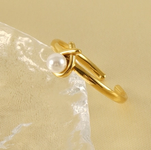 Close-up of golden stainless steel ring with a single white pearl and spiral design