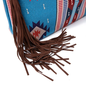 Detail of bohemian woven bag featuring blue geometric patterns and brown suede fringe trim