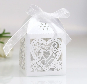 Close-up of laser-cut heart hollow design on white wedding candy box with silk ribbon