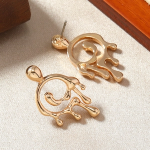 Macro shot of gold liquid droplet earrings featuring a fluid irregular metallic design