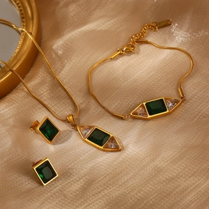 Parure bijoux dorée luxueuse avec pierres vert émeraude sur tissu de soie dorée brillante