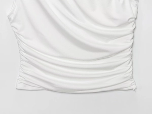 Detail of white knitted fabric with intricate ruching and pleated texture on the garment