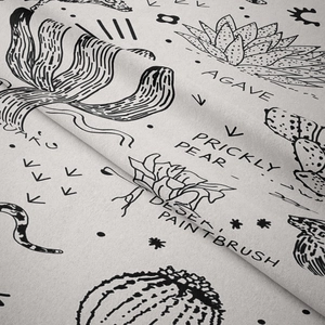 Close-up of bohemian tapestry fabric texture featuring hand-drawn desert plant patterns