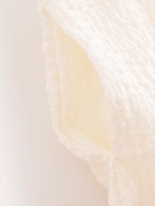 Close-up of cream-colored textured seersucker fabric with waffle pattern detail