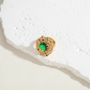 Macro detail of gold vintage ring featuring emerald cut green stone and colorful zircon accents