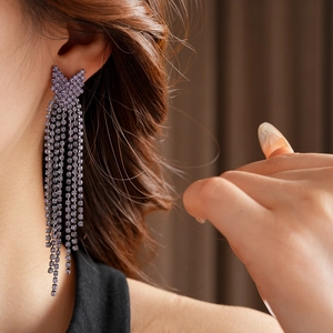 Gros plan de boucles d'oreilles à pampilles mauves avec cristaux sur un mannequin