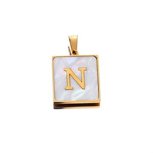Macro shot of 22mm gold square pendant featuring a white shell inlay with letter N detail